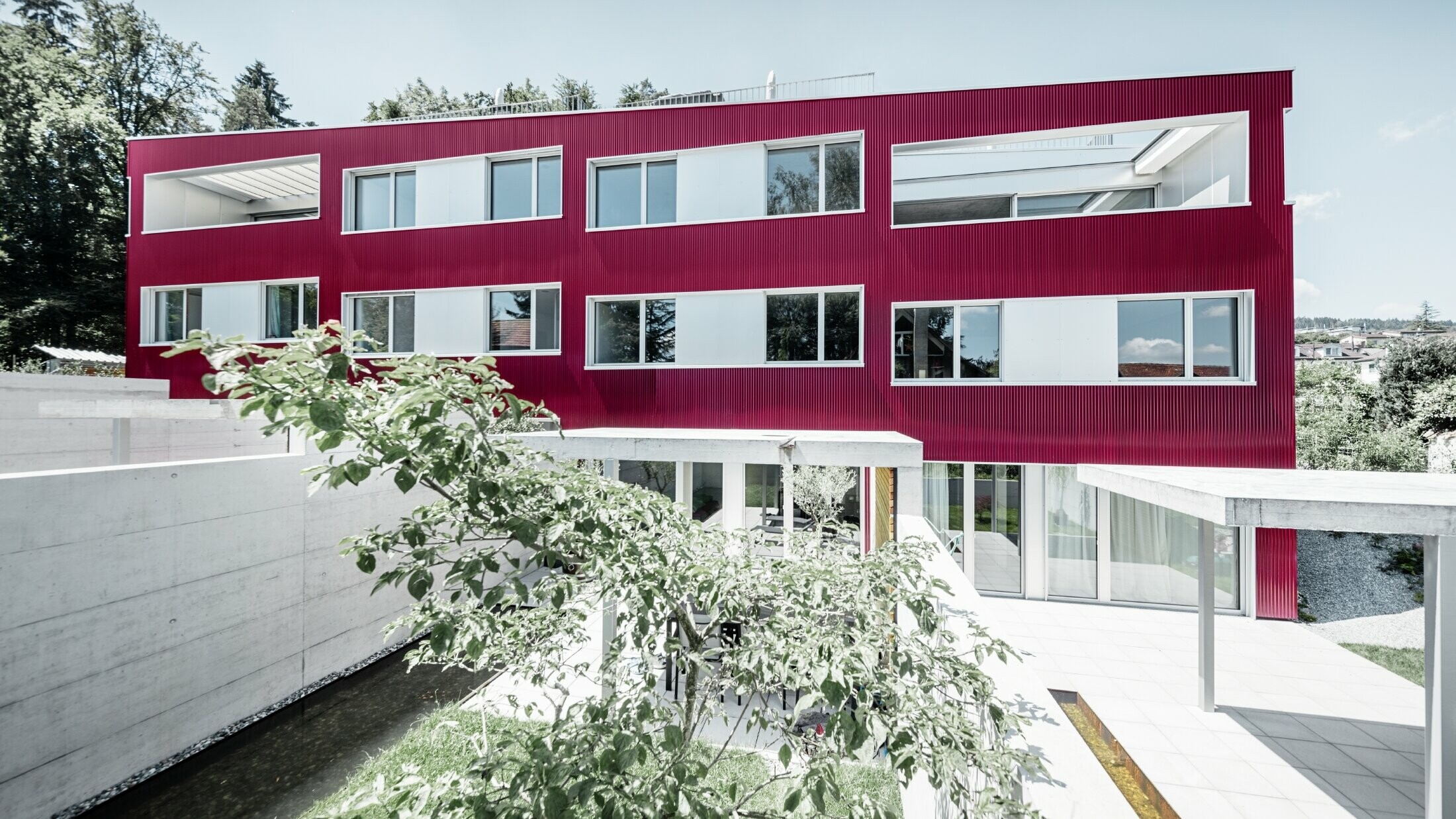 Apartment complex with flat roof and balconies with burgundy façade with PREFA ripple profile 