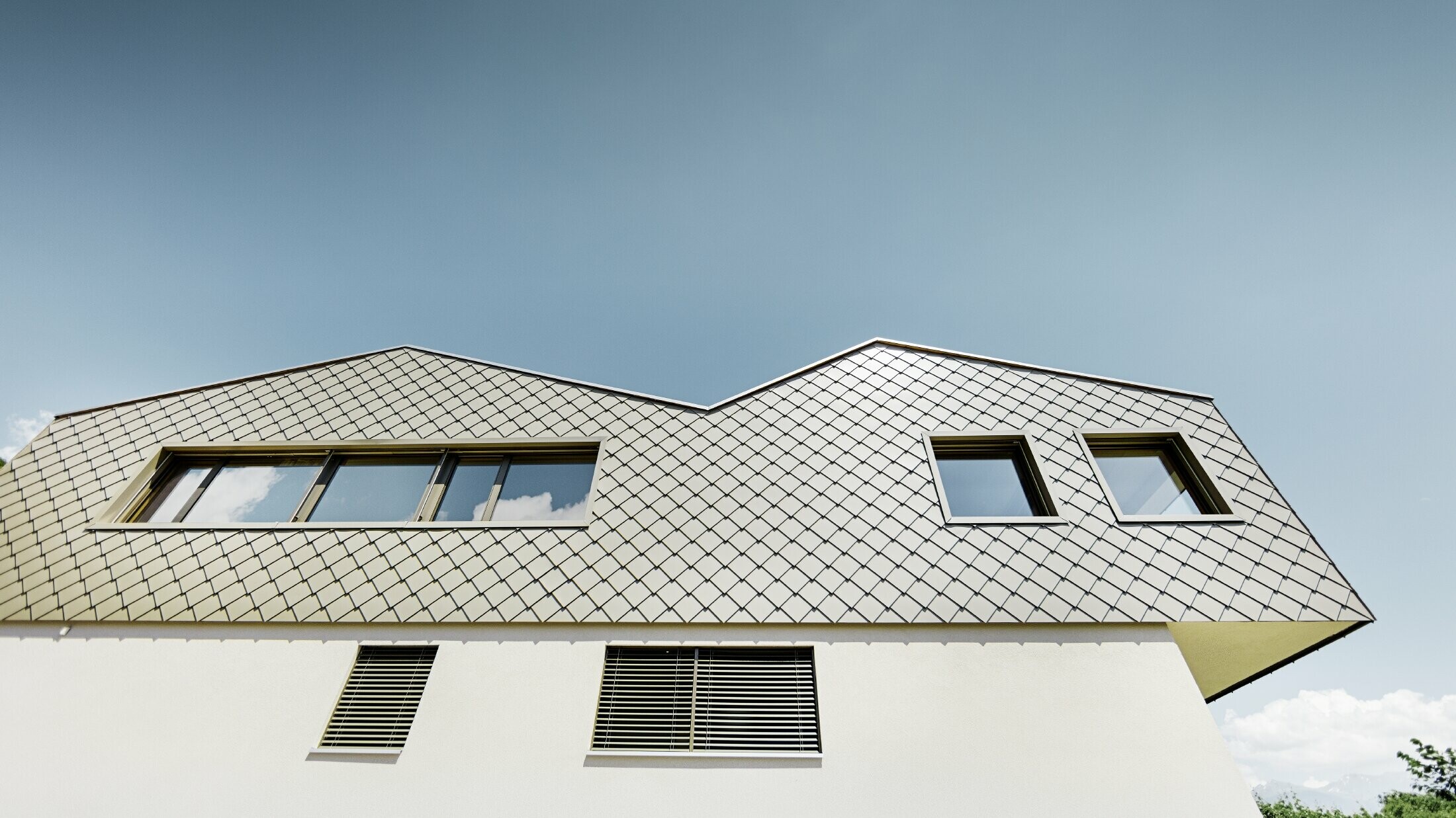 Modern detached house in the middle of the vineyards of the Rhône Valley with 4 different roof surfaces and an open gallery with a rhomboid tile façade in bronze