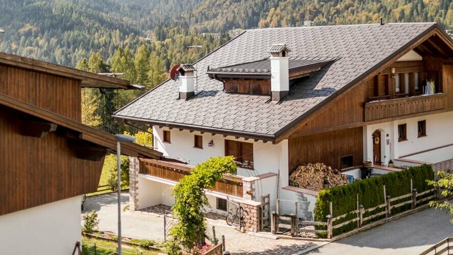 Traditional house with nut brown PREFA roof covering and a façade made of timber elements and render