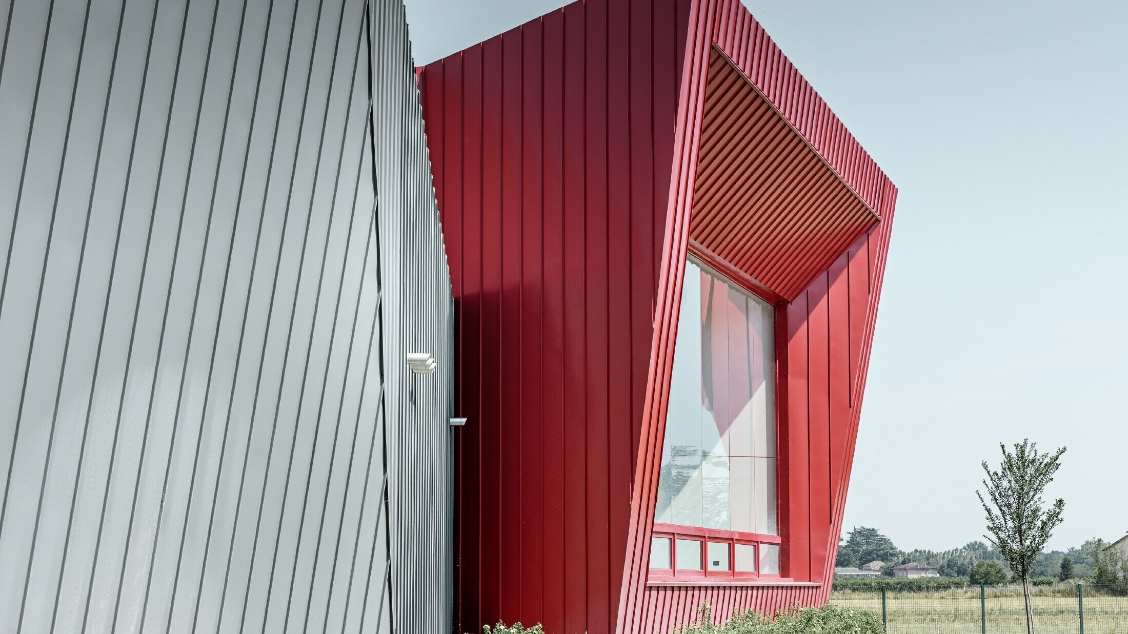 modern training centre by Dieci in Montecchio Emilia, Italy, with grandstand with aluminium façade with Prefalz in light grey and Falzonal in carmine red 