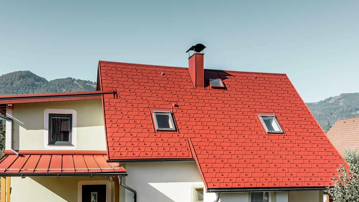 Classic single-family house with two skylights and chimney, roofed with the new PREFA DS.19 shingle in P.10 oxide red.