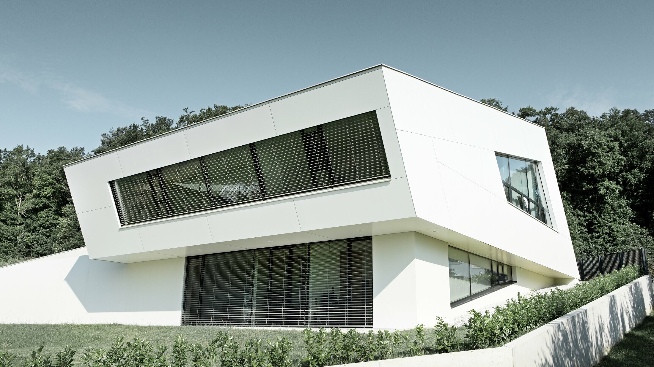 Very modern detached house with a white PREFA composite panel façade and large windows