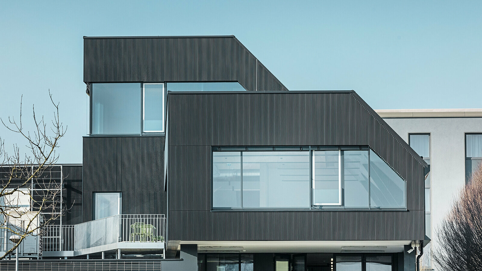 Side view of the Amann café on a sunny day. A corrugated profile in black was used to protect the building.