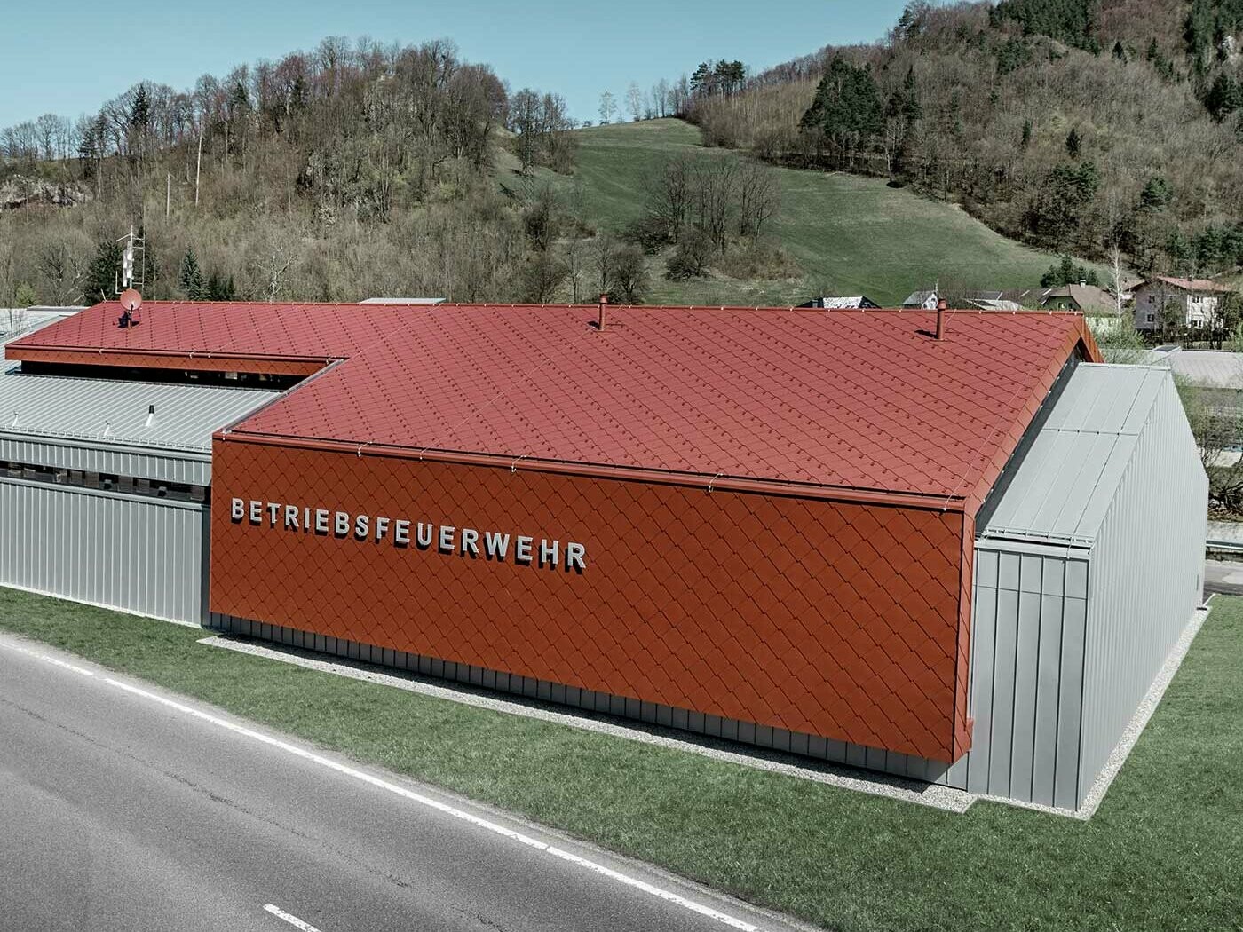 The new fire station for PREFA and Neuman Aluminium’s own fire brigade was clad with the new 44 × 44 rhomboid roof and wall tiles in P.10 oxide red and Prefalz in metallic silver.
