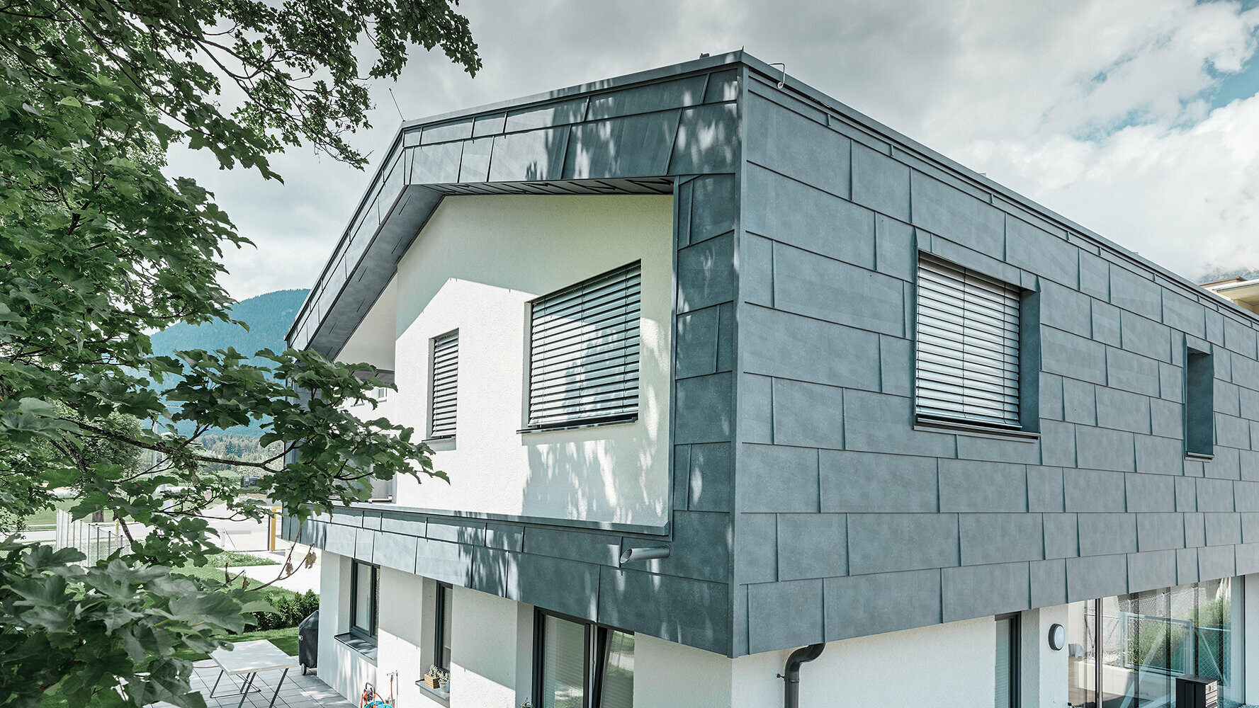 Modern detached house without eaves; the upper floor was  clad with PREFA FX.12 façade panels in stone grey, the rest of the façade was plastered white.