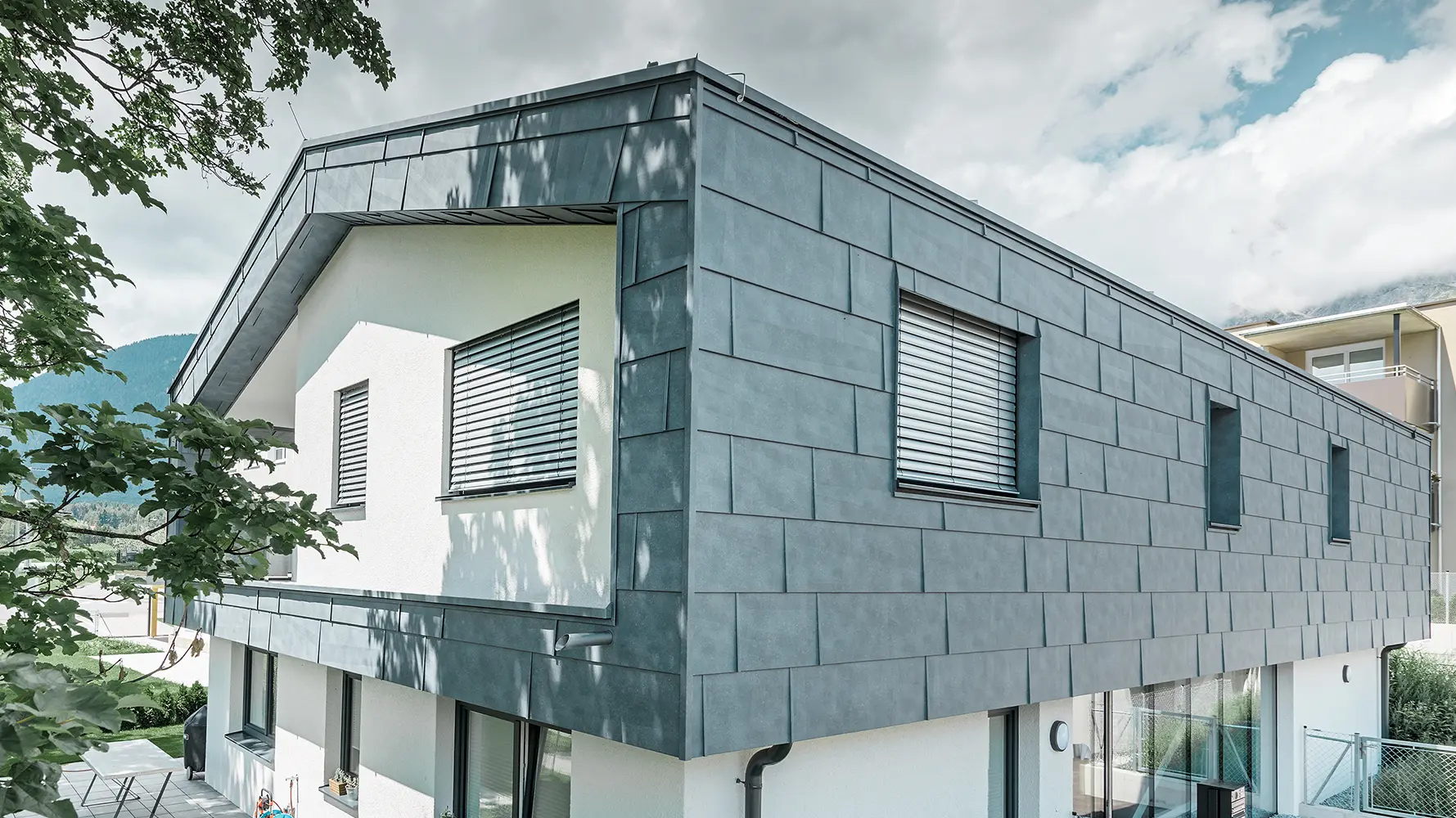 Modern detached house without eaves; the upper floor was  clad with PREFA FX.12 façade panels in stone grey, the rest of the façade was plastered white.