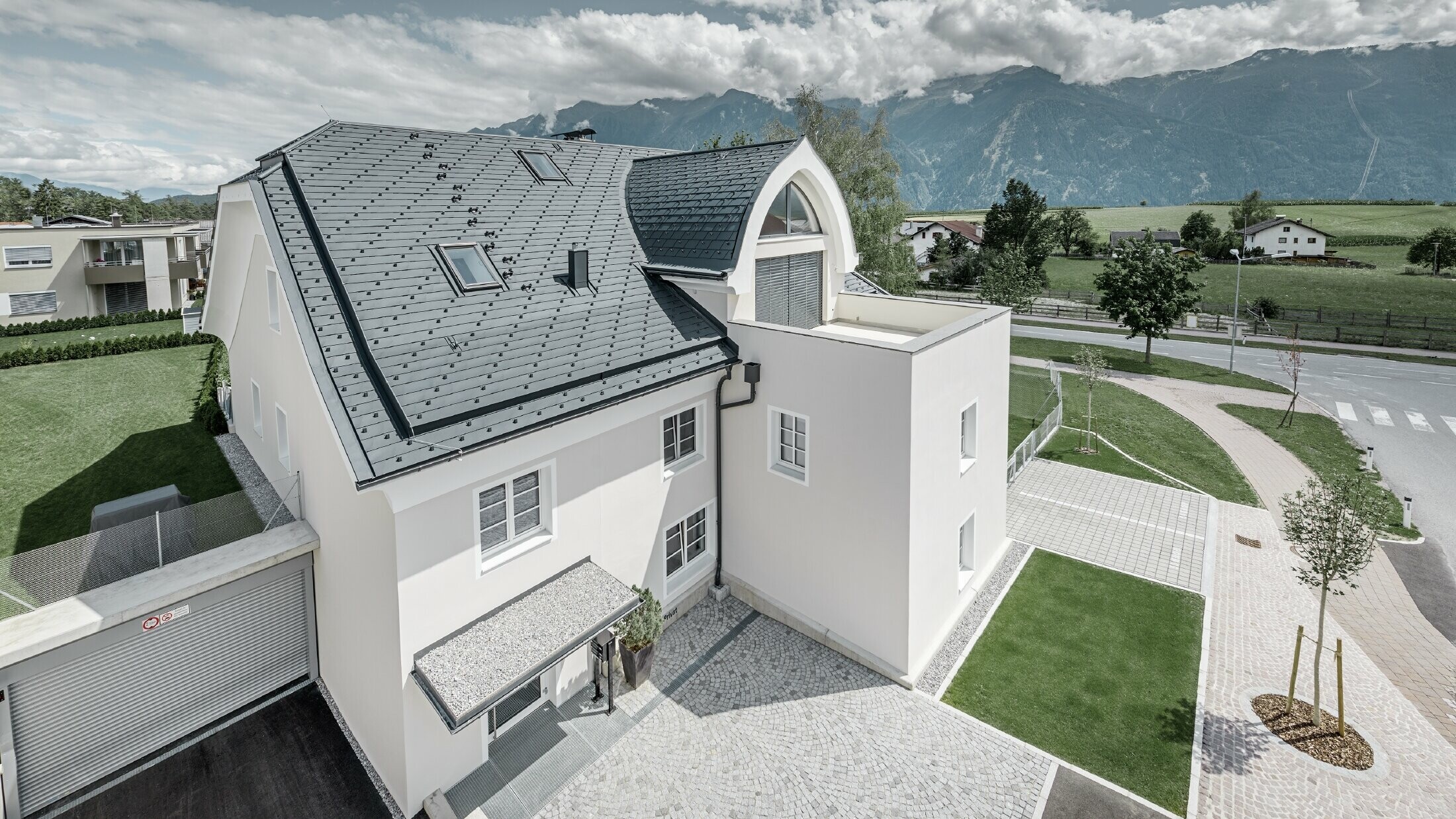 Newly refurbished residential building with new PREFA roof. The half hipped roof with pointed barrel dormer and loggia were covered with PREFA aluminium shingles in anthracite. PREFA snow guards, window surround and gutters were also installed.