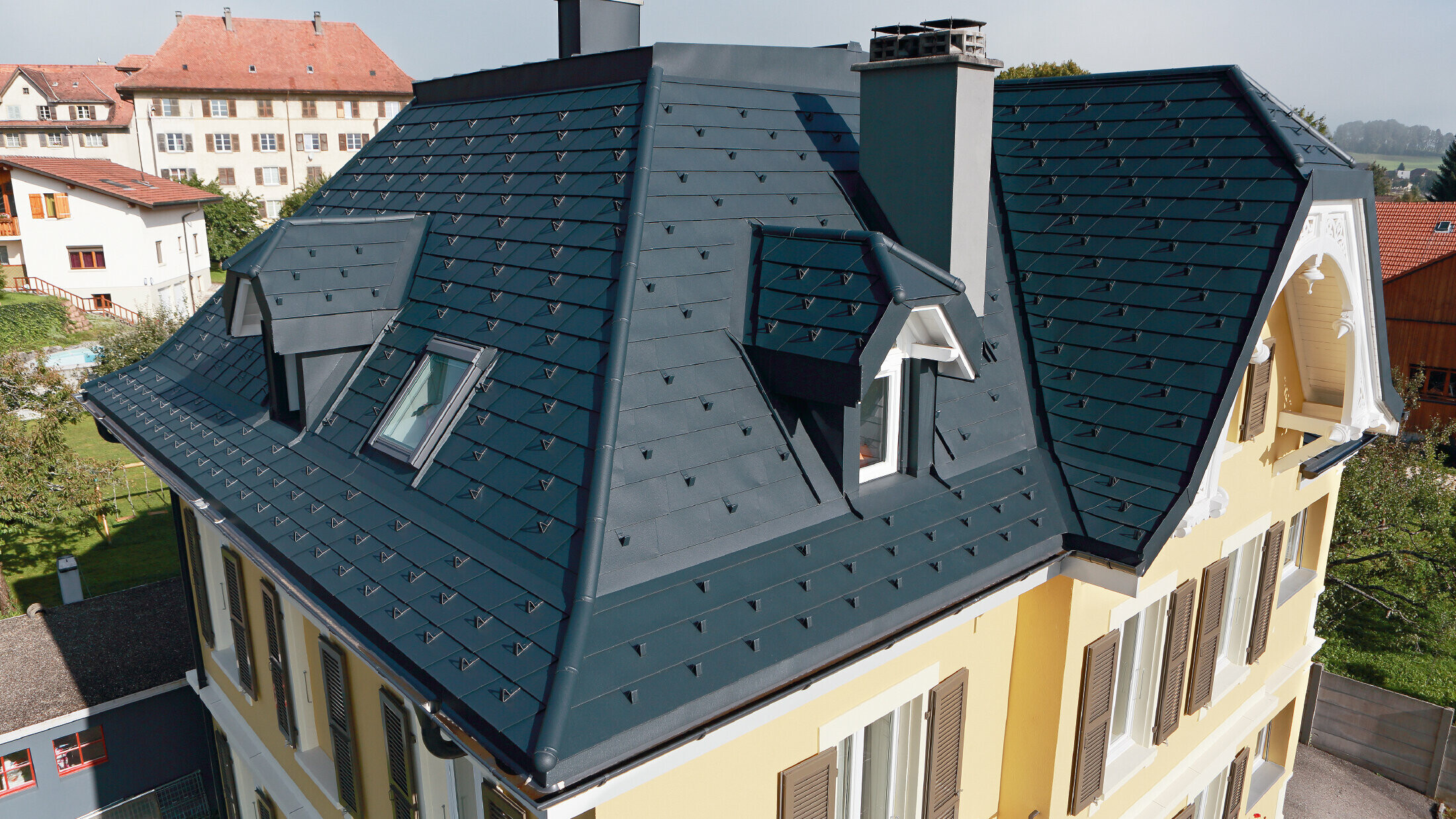 Villa in Switzerland, the roof has many valleys and small dormers, the roof is covered with an aluminium shingle from PREFA in P.10 anthracite.
