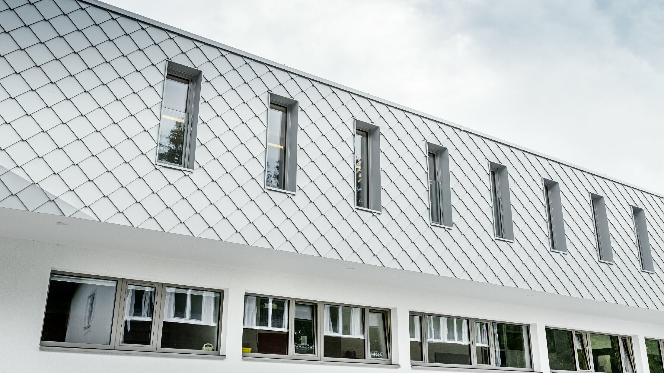 Newly built kindergarten in Kaprun with a modern aluminium façade with the PREFA rhomboid façade tile in PREFA white