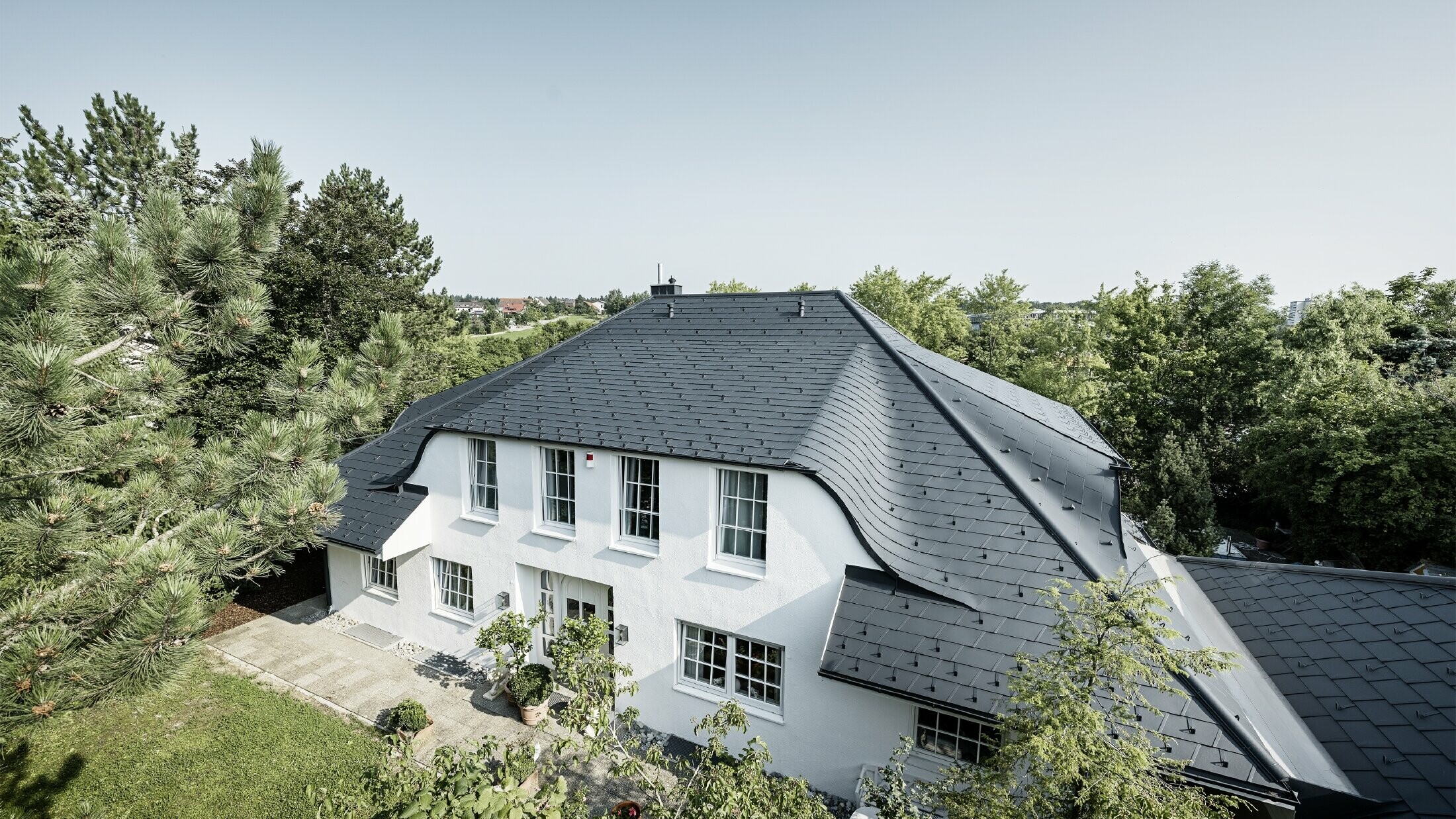 Hipped roof with many curved dormers, covered with DS.19 aluminium roof shingles in anthracite