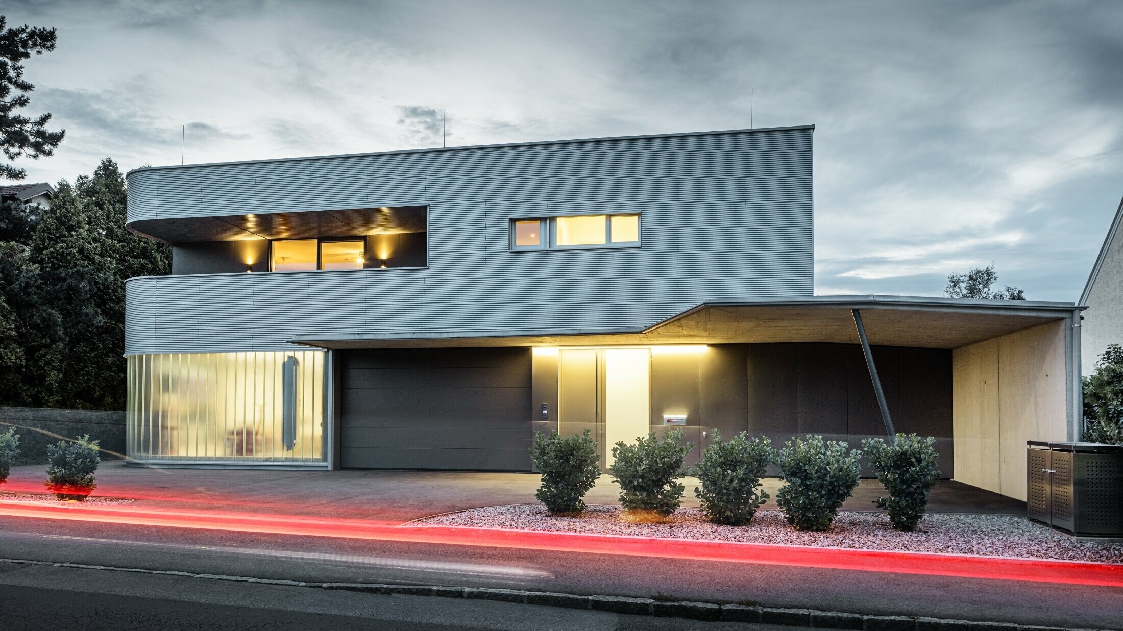 Modern residential building with plain aluminium façade made of the PREFA ripple profile with garage, photographed in evening light