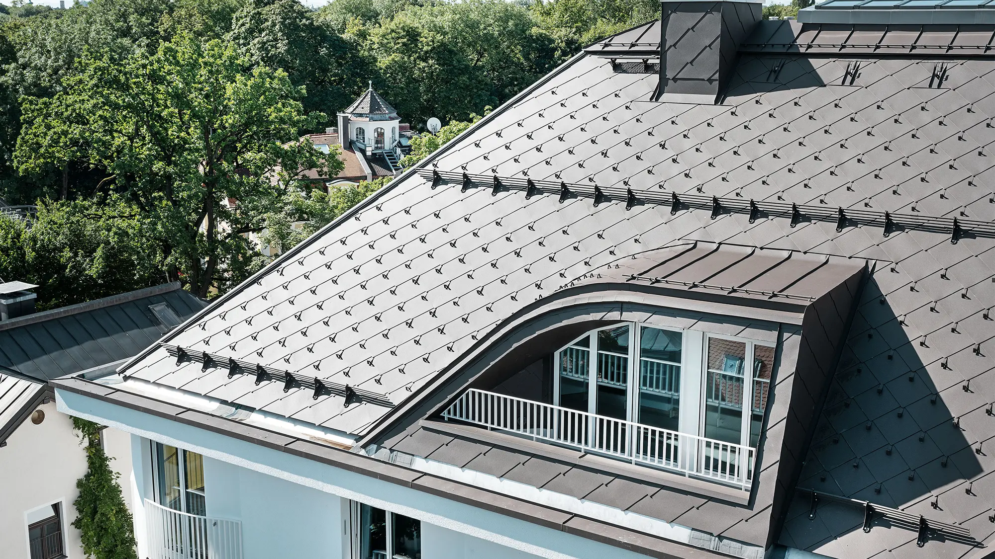 Apartment building with PREFA rhomboid roof tiles 44 × 44 in brown with snow guards and snow rakes