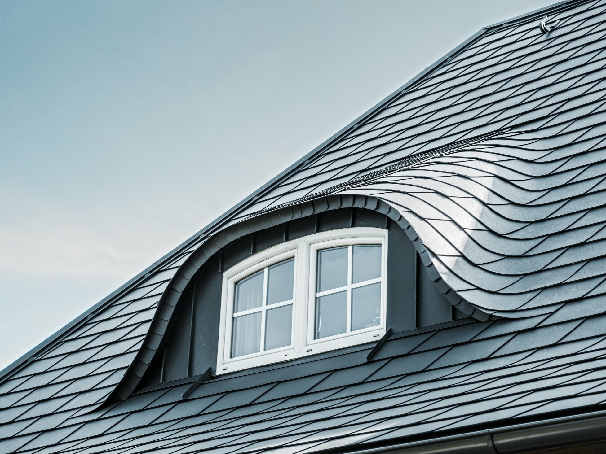 newly renovated roof with curved dormer with window covered with aluminium roof shingles by PREFA in P.10 anthracite 