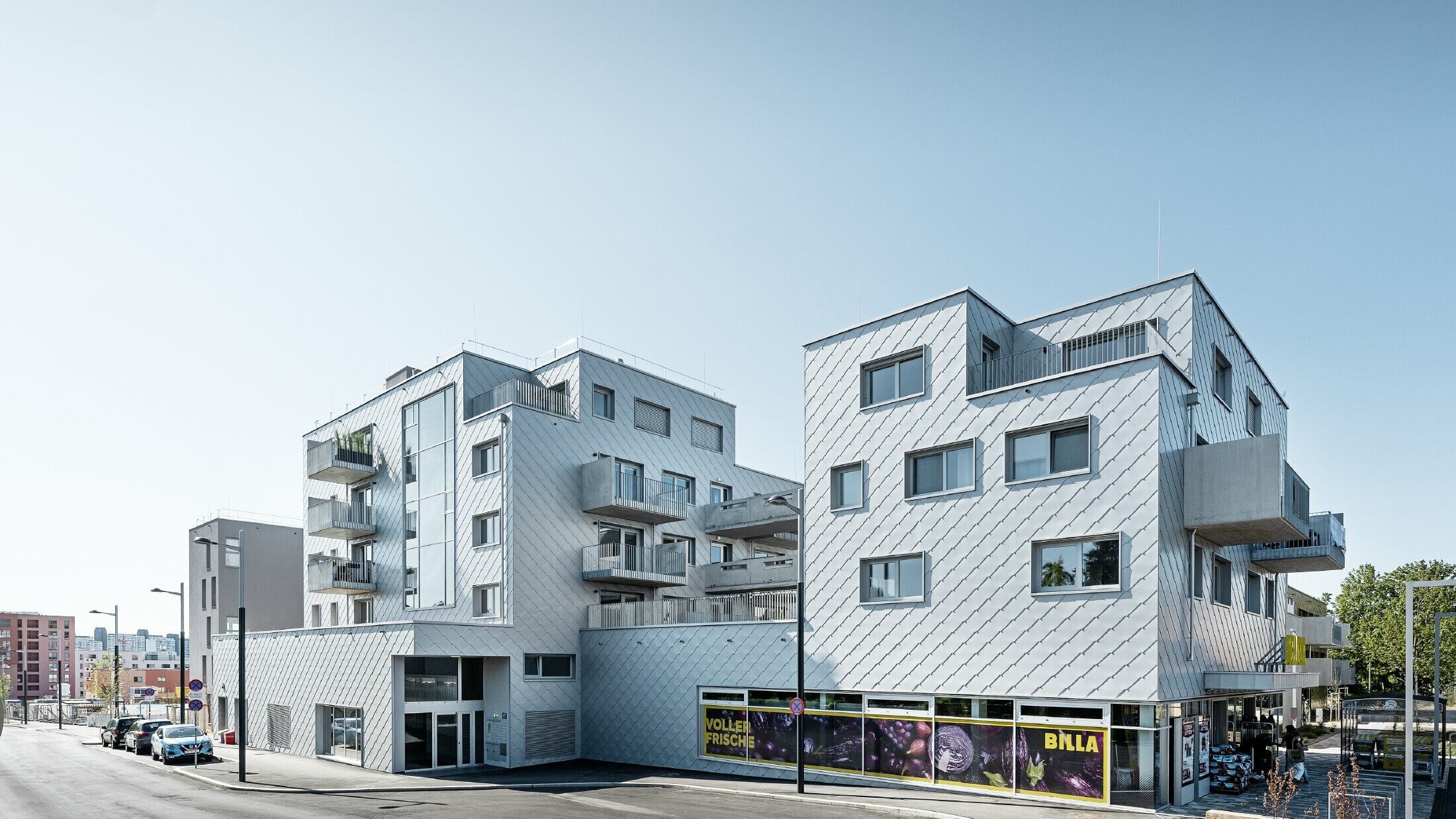 Apartment complexes with flat roof and rhomboid cladding on the façade with PREFA 44 × 44 rhomboid façade tiles in metallic silver