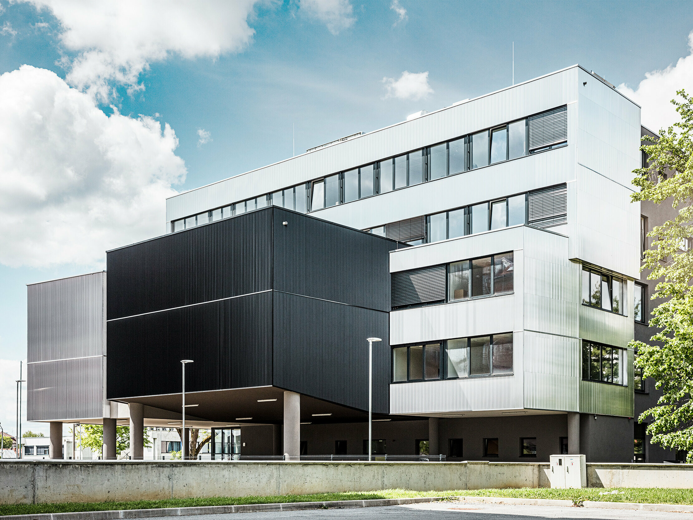 Side view of the music school in Bjevolar with a modern PREFA façade in a serrated profile. The façade is finished in black and bare aluminium, and the geometric shapes create a striking, minimalist design.