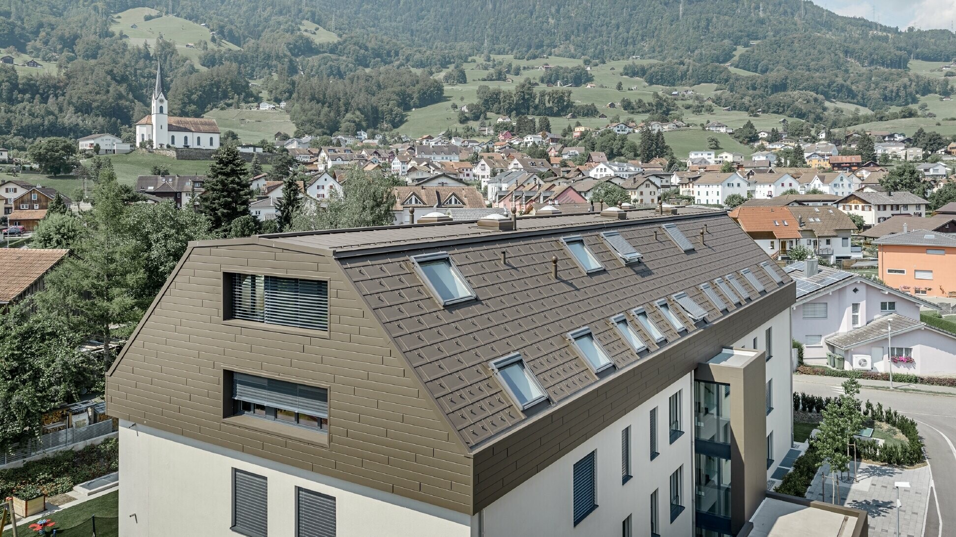 The upper floors of the apartment building were clad in the PREFA siding and R.16 roof tile in brown. Numerous roof windows are visible.