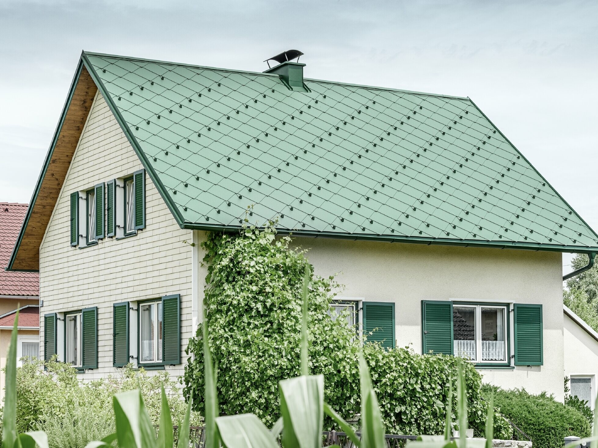 Classic detached house with a gable roof with an aluminium roof covering in moss green with green shutters