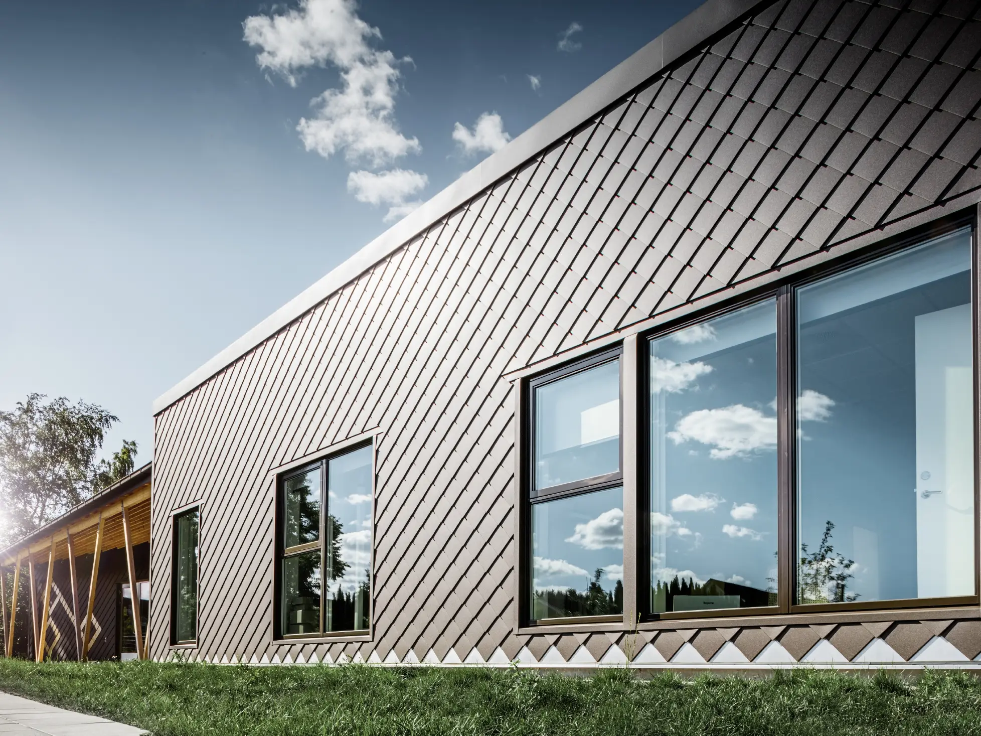 This image of a pre-school in Stockholm shows the new façade with large windows and a flat roof. The exterior façade was clad with the rhomboid façade tile 20 x 20 in brown.