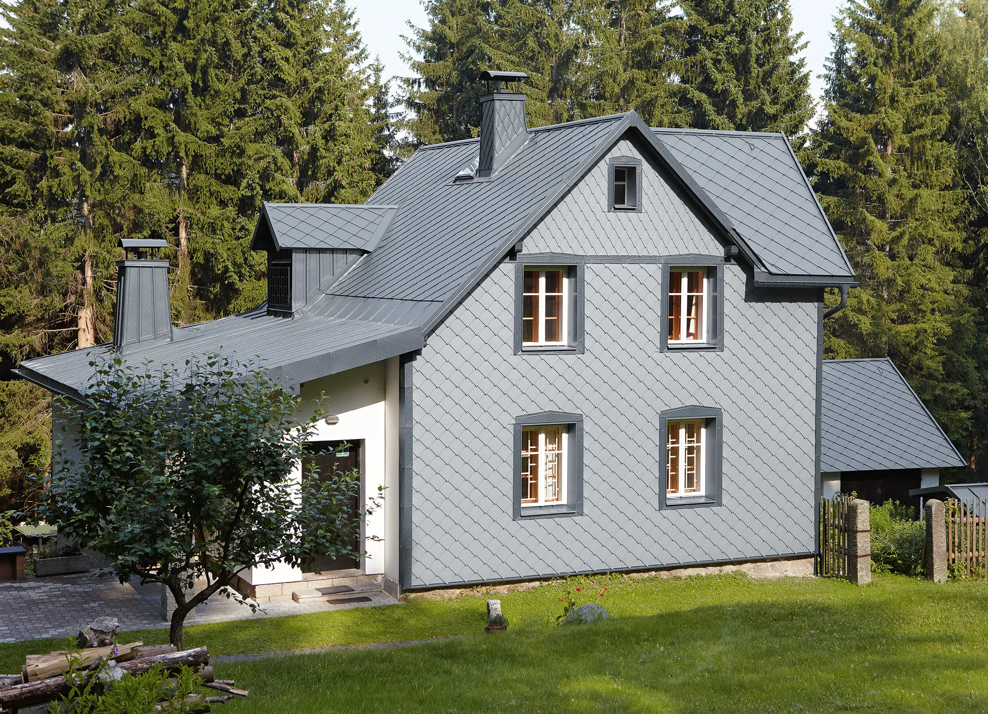 Detached house in a wooded area with a weather-resistant PREFA aluminium façade in light grey.