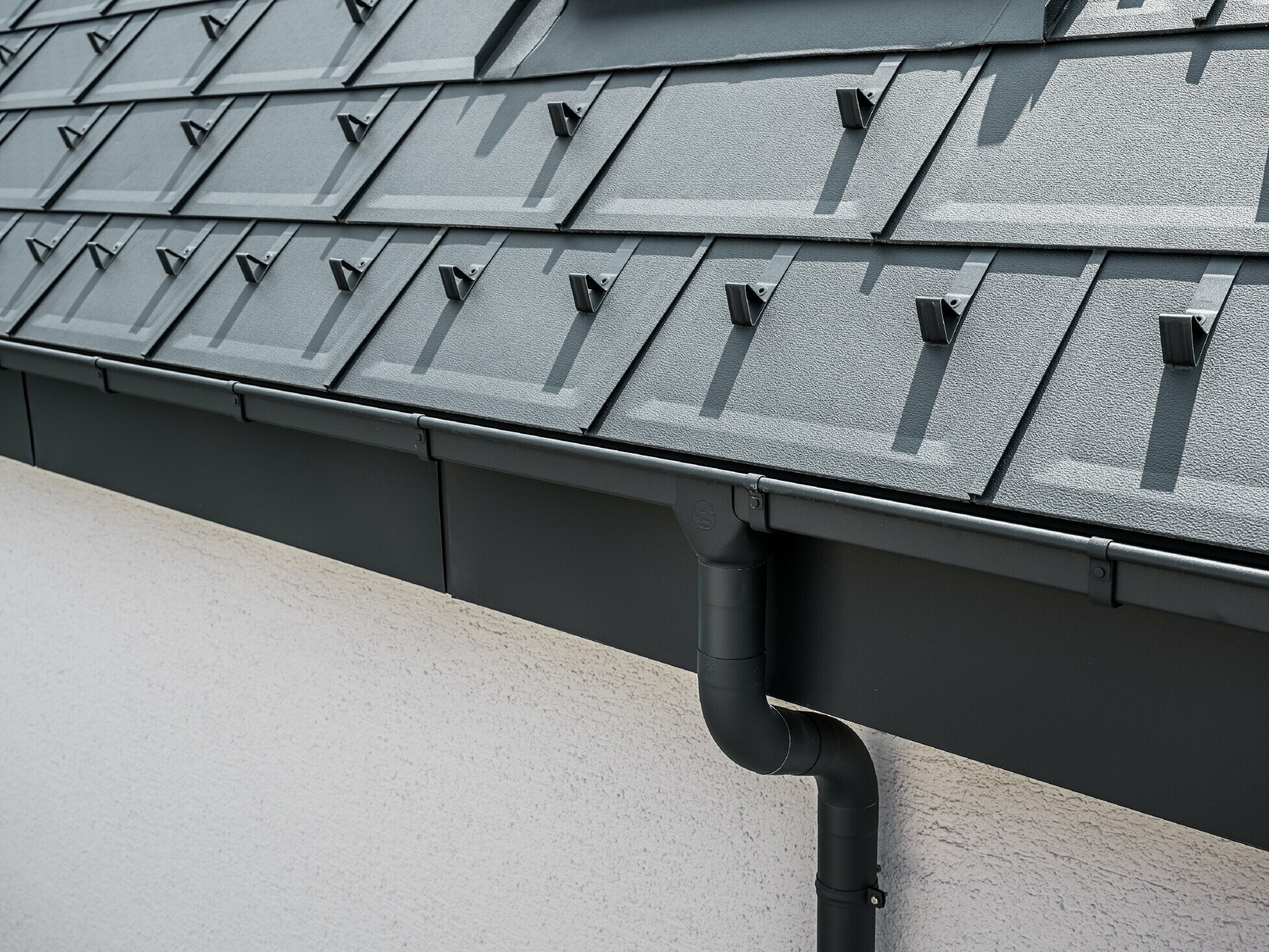 Steep roof surface covered with the roof tile R.16 with square PREFA box gutter with gutter outlet and downpipe in anthracite