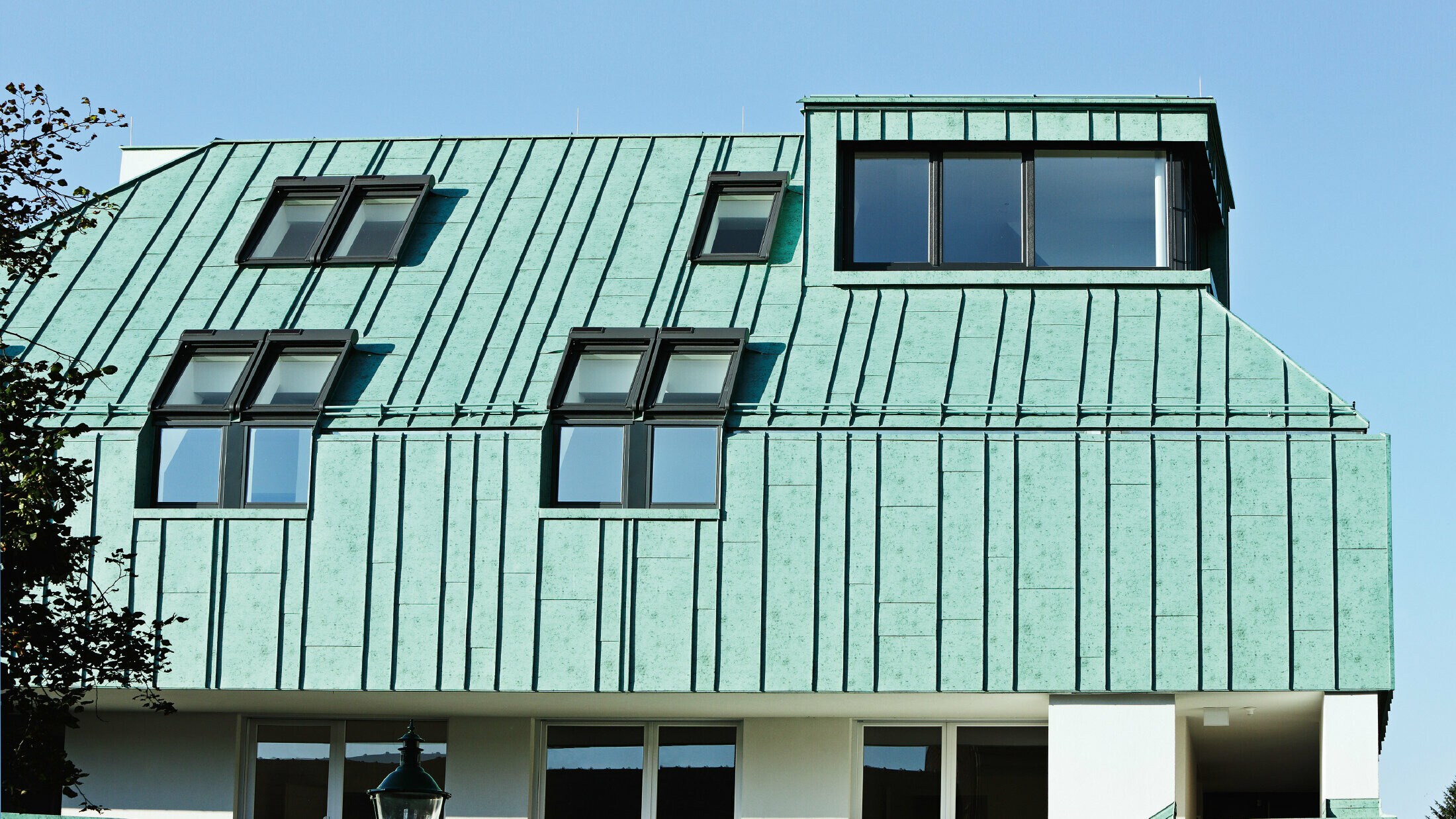 Roof and façade design with PREFALZ in patina green from PREFA in different panel widths.