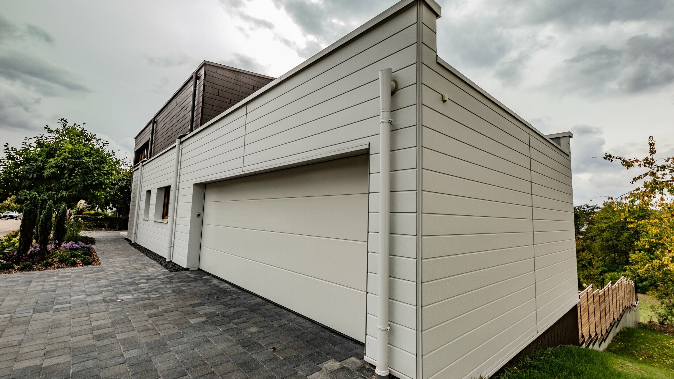 Garage cladding with horizontally installed PREFA siding in white together with the PREFA parapet outlet connector.