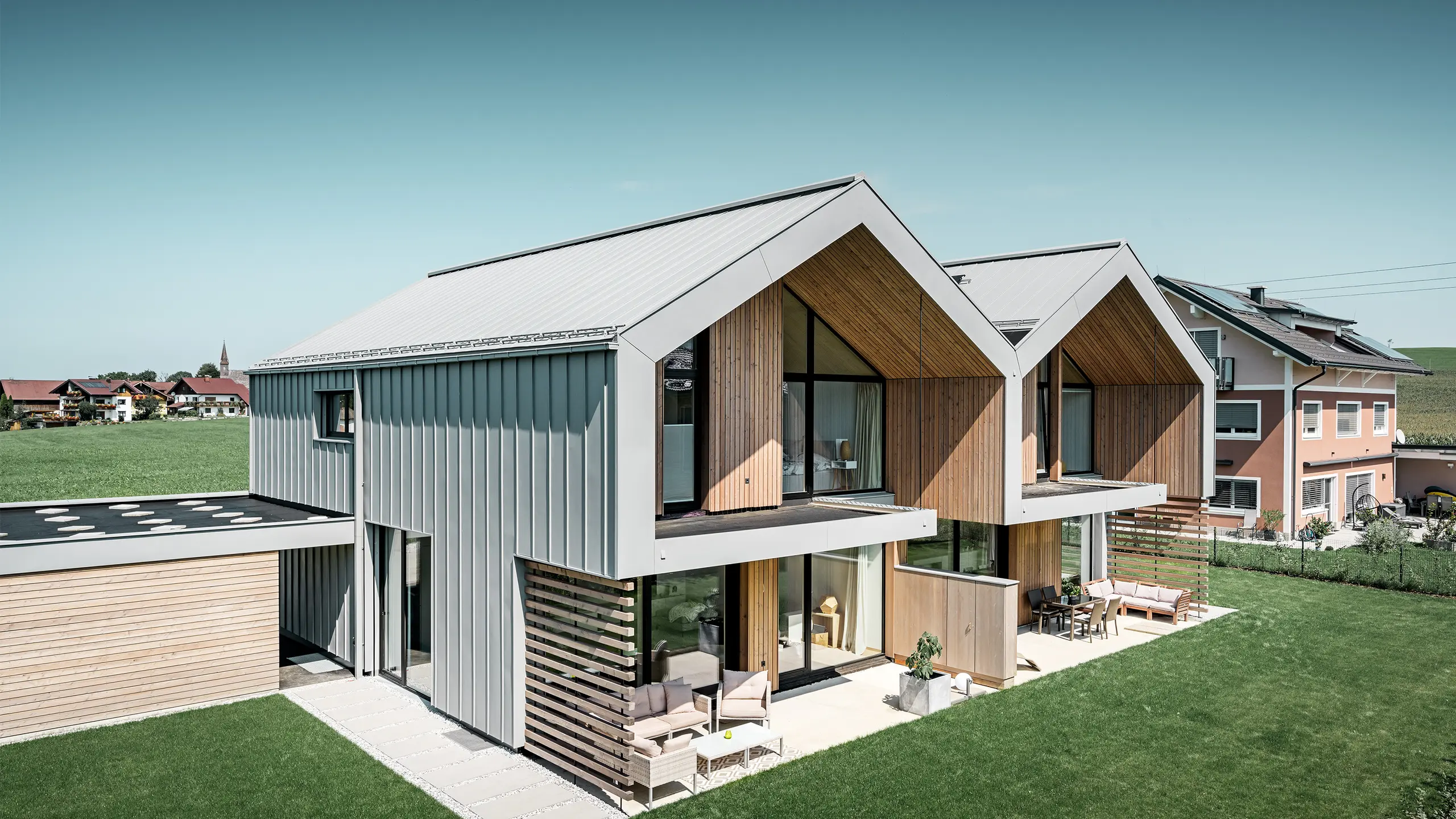 Modern semi-detached houses with PREFALZ (standing seam) building shell, roof and façade are clad with PREFALZ standing seam in patina grey incl. square downpipe